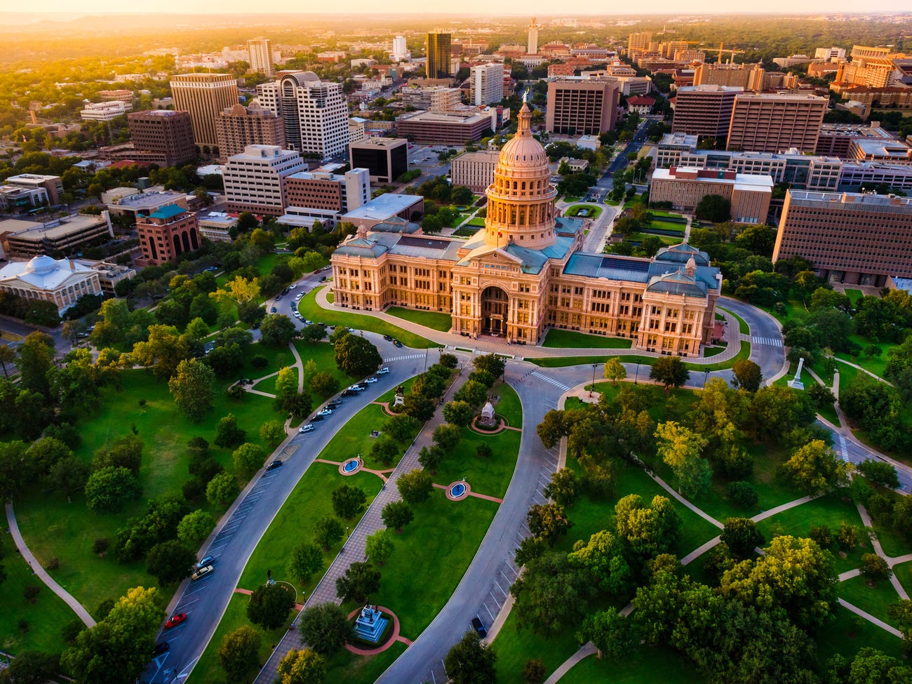 Sunset over a state capitol building rotunda butting against a downtown skyline