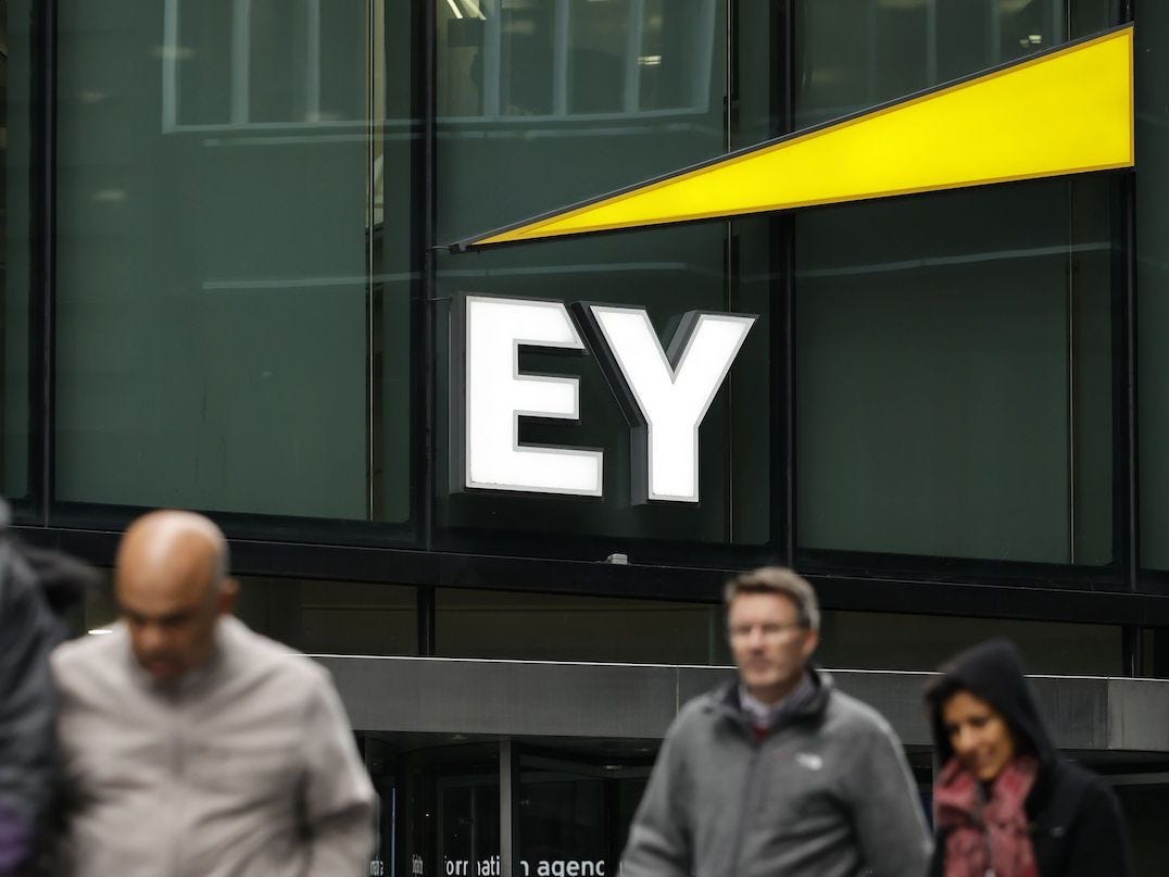 Pedestrians walk in front of the entrance to EY's head office in London.